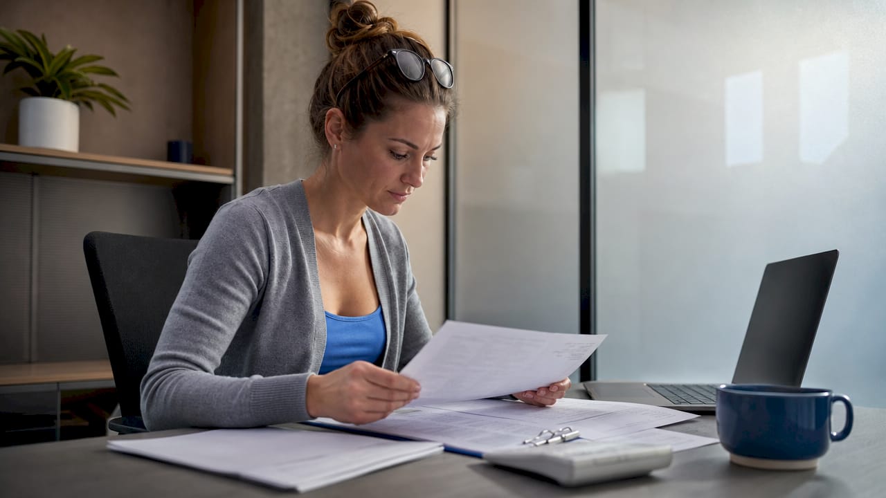 Small business owner reviewing housekeeping invoices at desk